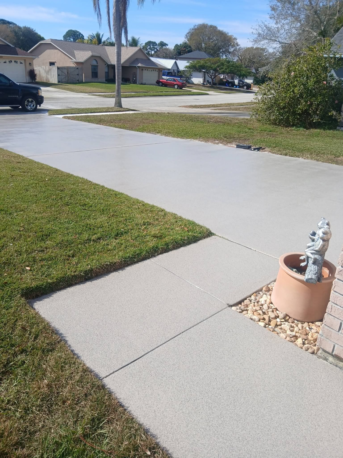 Wide view of a freshly coated gray driveway and front walkway
