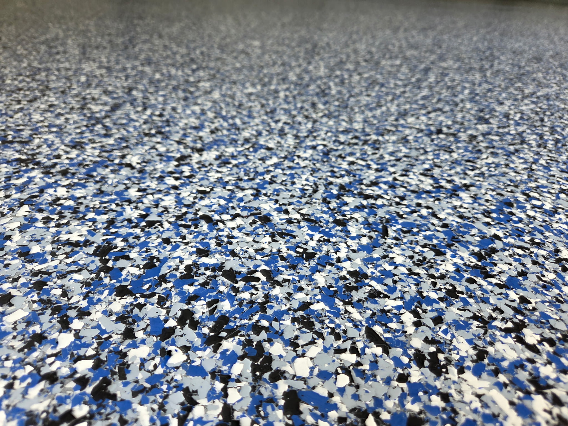 Close-up of a blue, white, and black epoxy flake floor with polyaspartic topcoat