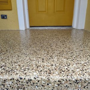 Tan, brown, and black full-broadcast flake epoxy coating on a covered patio entry