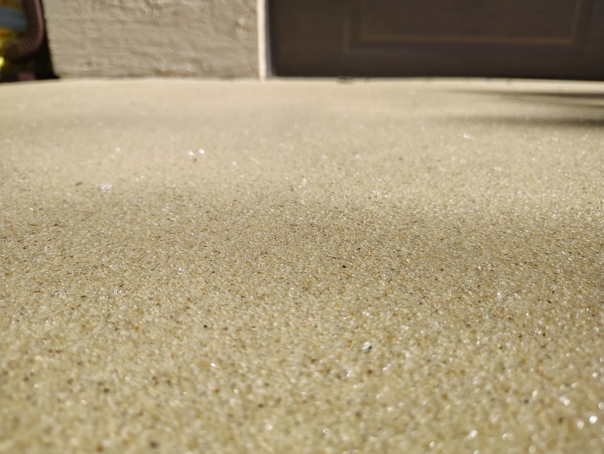 Close-up of a sand-colored quartz aggregate epoxy floor coating at a residential entryway
