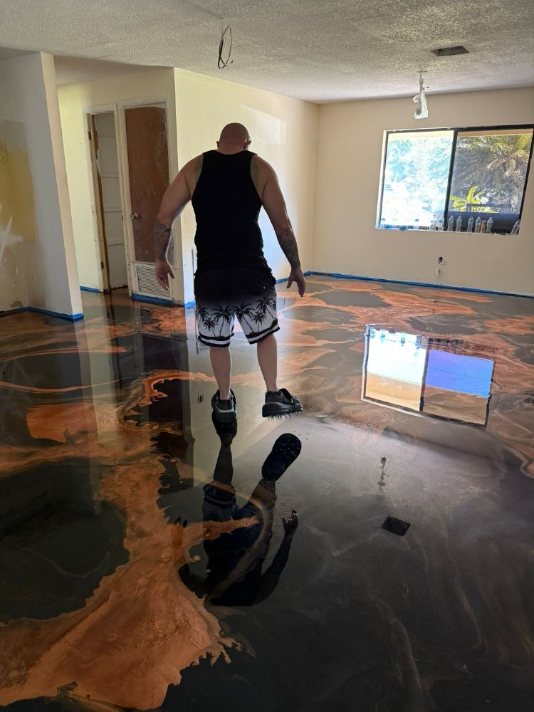 Black and copper-gold swirling metallic epoxy floor being poured indoors in Mims, FL