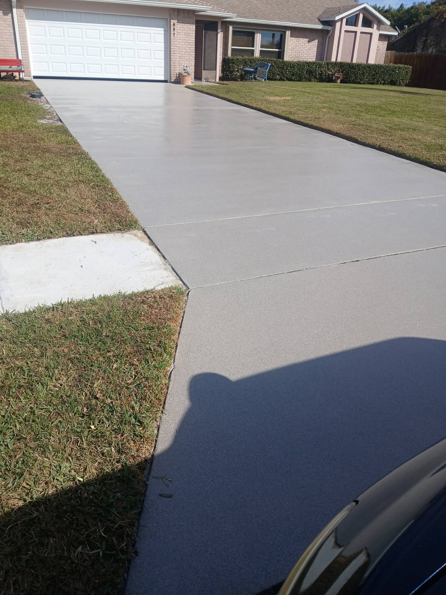 Gray epoxy-coated concrete driveway leading to a two-car garage